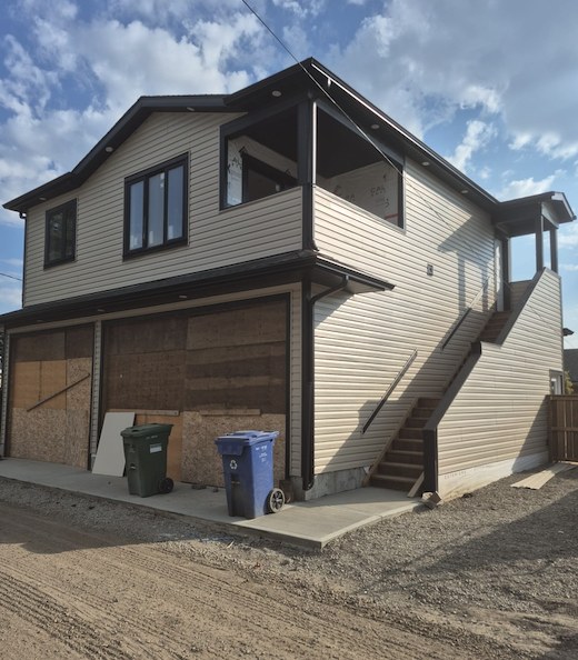 Detached garage with a suite above, cream siding and dark trim built by HDL Construction