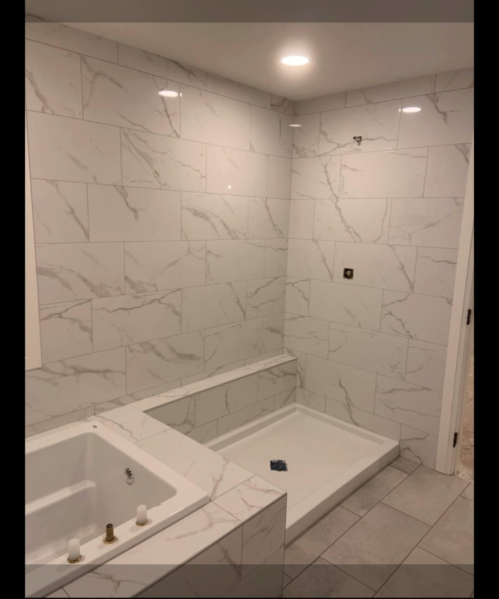 Bathroom with marble-look wall tile, tiled tub deck and shower base