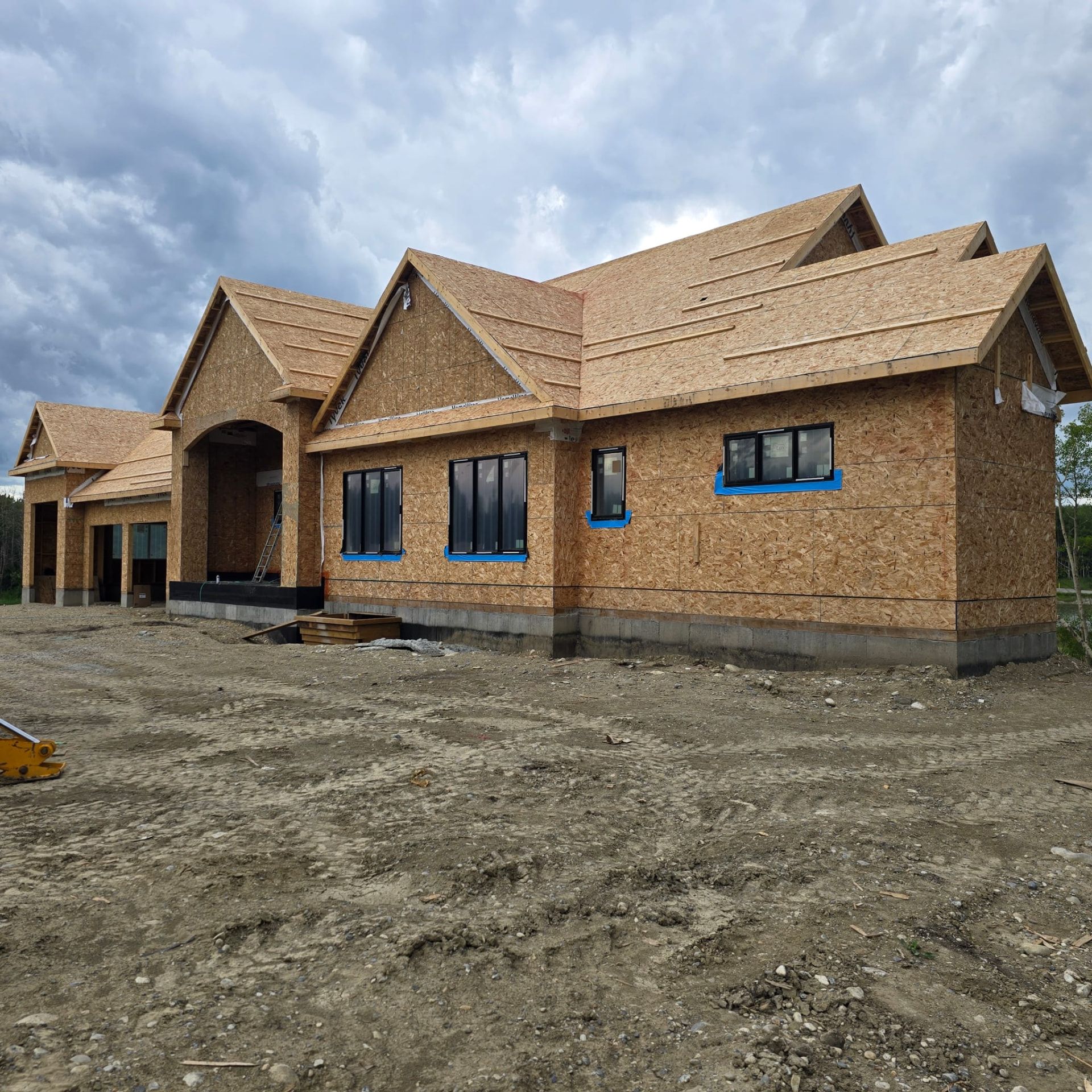 Large bungalow with sheathing, roof and black windows installed